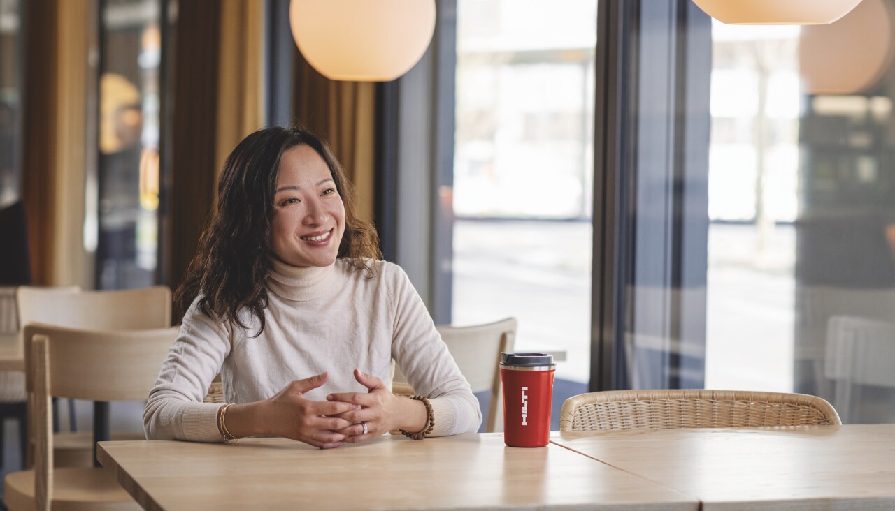 Une collaboratrice Hilti souriant avec un mug Hilti