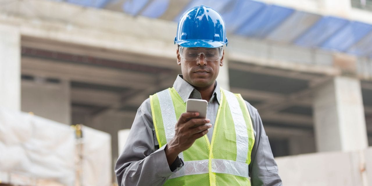 Portrait of a male Indian builder or industrial engineer at work using phone.